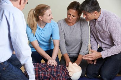 Woman Demonstrating CPR On Training Dummy In First Aid Class