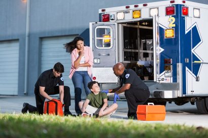 Injured boy with two paramedics, adult female and ambulance